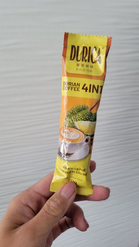 A hand holding up a package of instant durian coffee