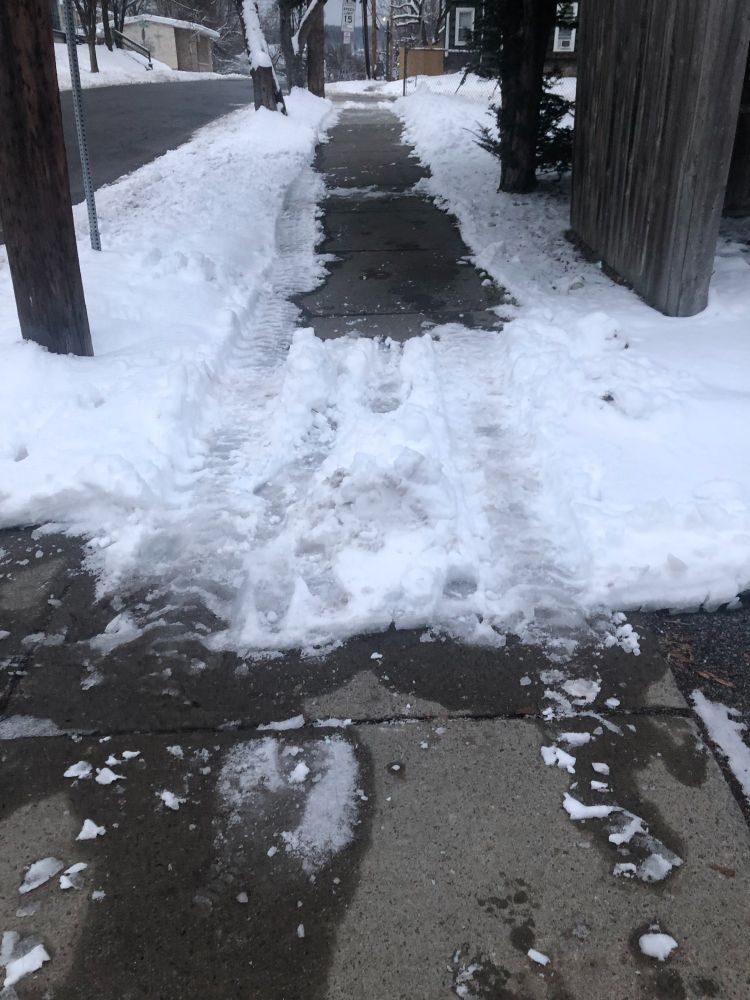 Several feet of uncleared icy sidewalk between two long cleared stretches. 