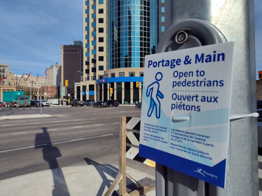 A sign affixed to a standard tells people that Portage & Main will be open to pedestrians starting June 27, 2025!