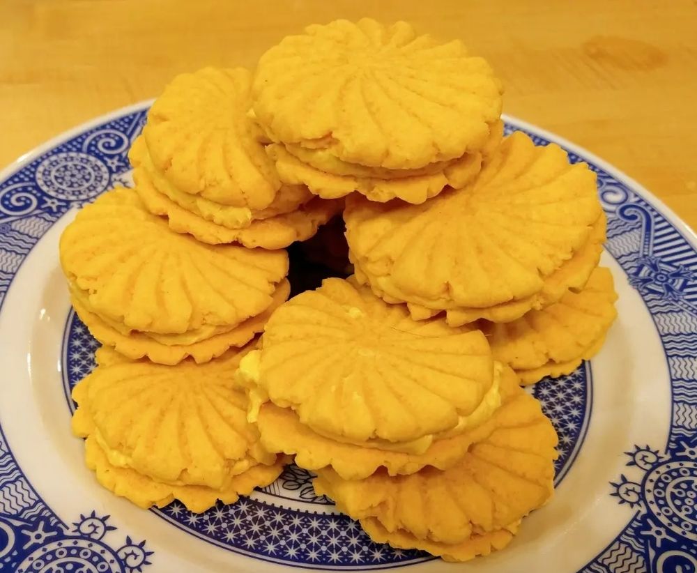 A stack of unevenly sized freshly baked Custard Creams.