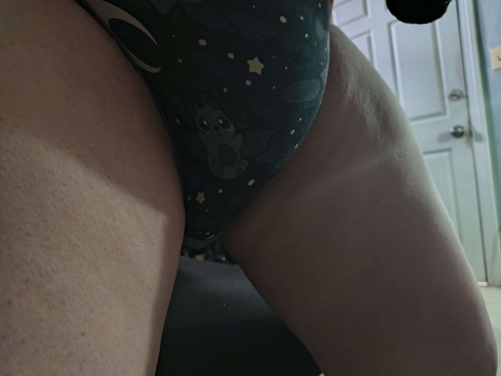simple selfie photo of a onesie bulging at the crotch with a soaked megamax beneath but from a 3/4 angle
