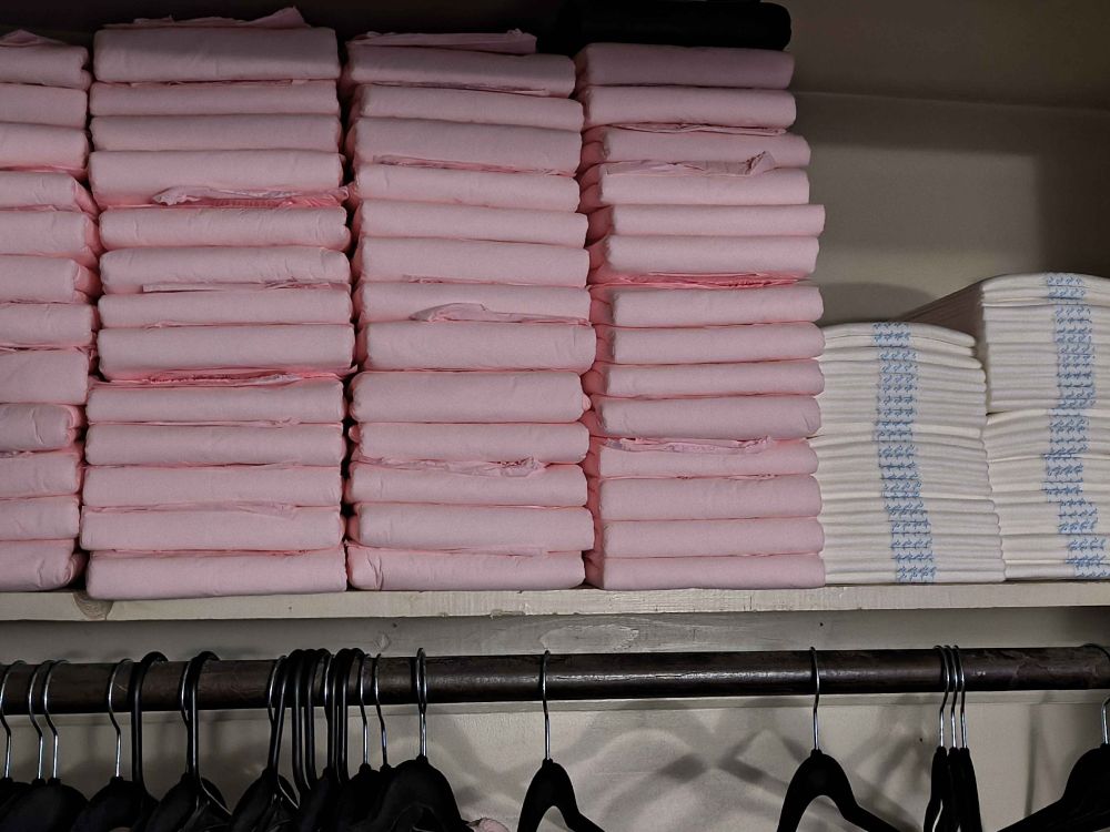 4 columns of pink northshore megamax diapers stacked in a closet shelf next to two shorter stacks of boosters