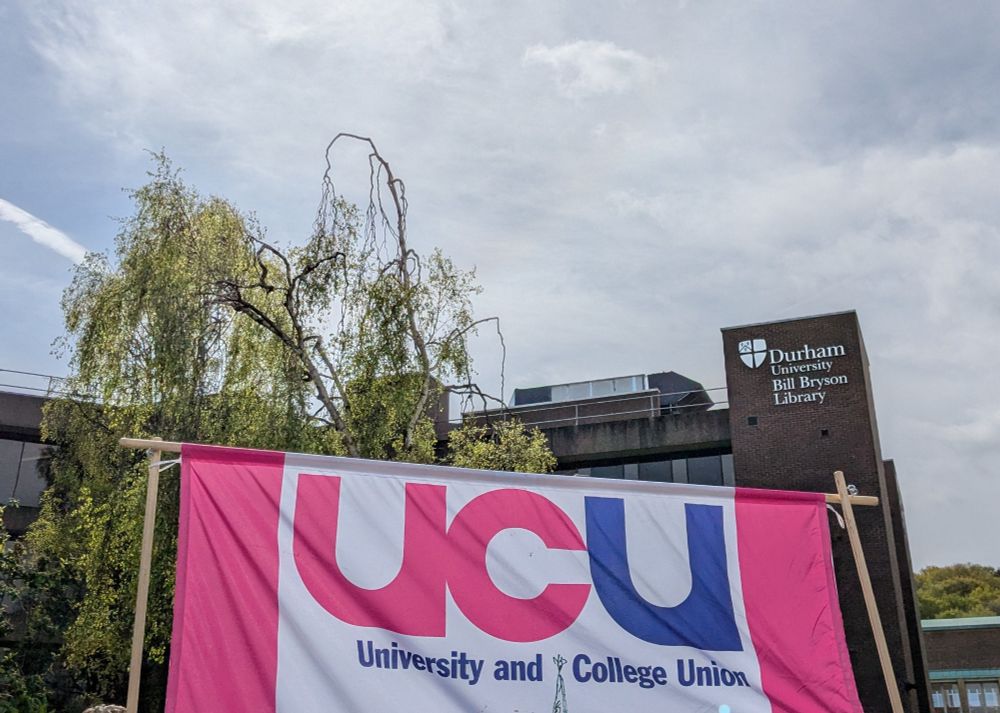The Durham UCU pink and blue banner in front of the university library 
