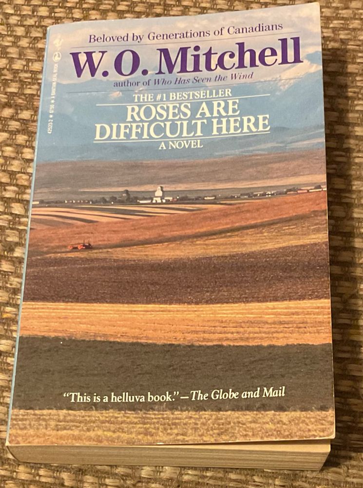 Cover of Roses are Difficult Here by W.O. Mitchell, with an image of vast farm fields and mountains in the distance.