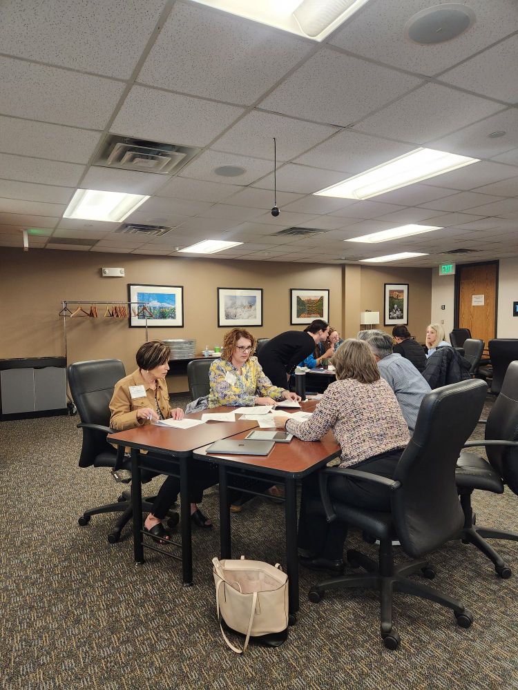 Photo a group of people sitting at a desk, working together and another group can be seen in the background. 