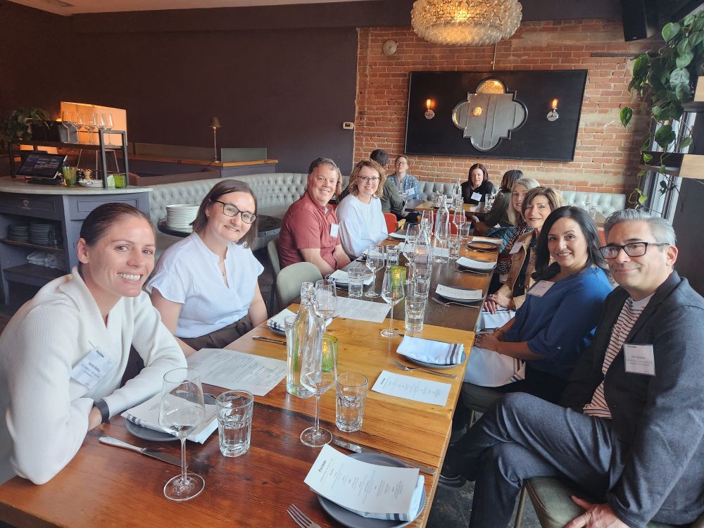 Photo of a group of eight people at a table in a restaurant smiling. 