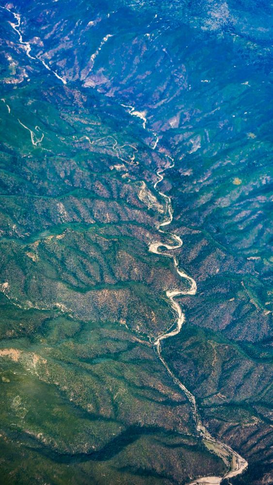 Picture of a river running through a mountain range, seen from a high angle. 