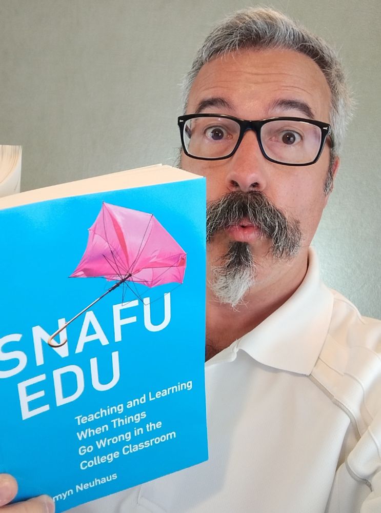 Tom Tobin makes the wide-eyed "ooh" face while he reads the book _Snafu Edu_ by Jessamyn Neuhaus.