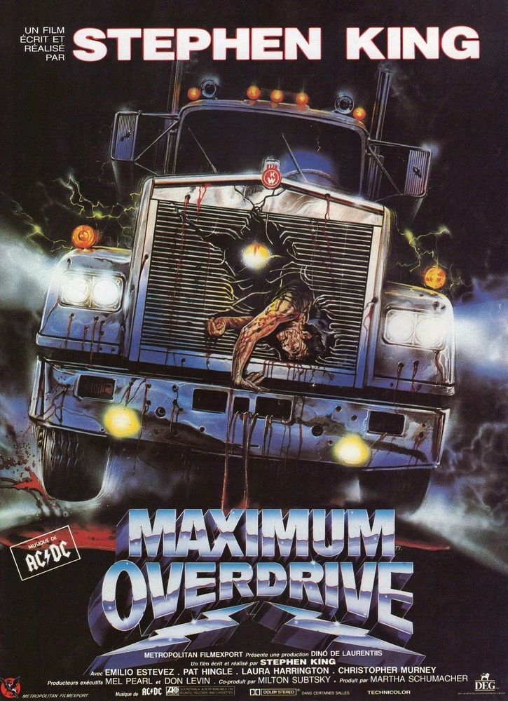 The poster for maximum overdrive. The front of a large truck is shown. With a dead body hanging gout of the damaged grille.