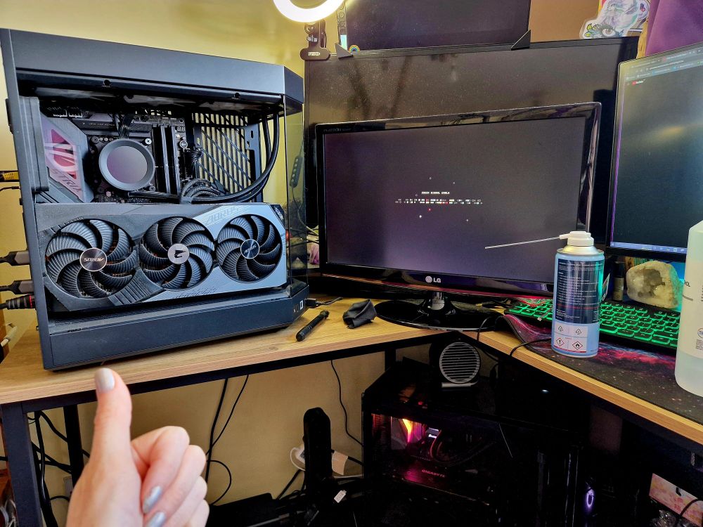 Pc on left with cover off and dusting clean brushes to the centre of the image. 4 screens and a can of compressed air to the right. 