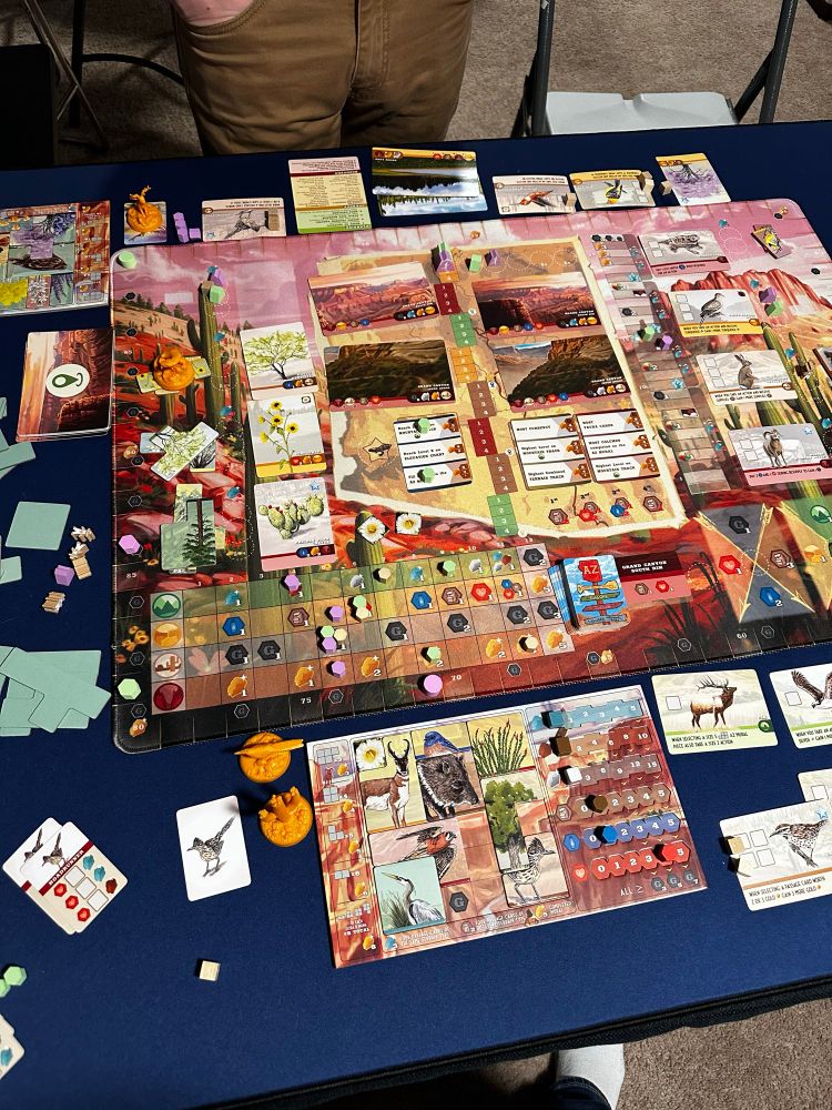A board game on a table. The game has a map of the Arizona trail and features many Arizona colors like copper and turquoise. 