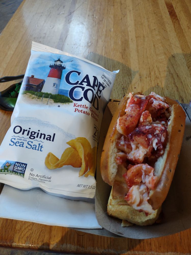 A hot buttered lobster roll in a toasted bun with a bag of Cape Cod chips.