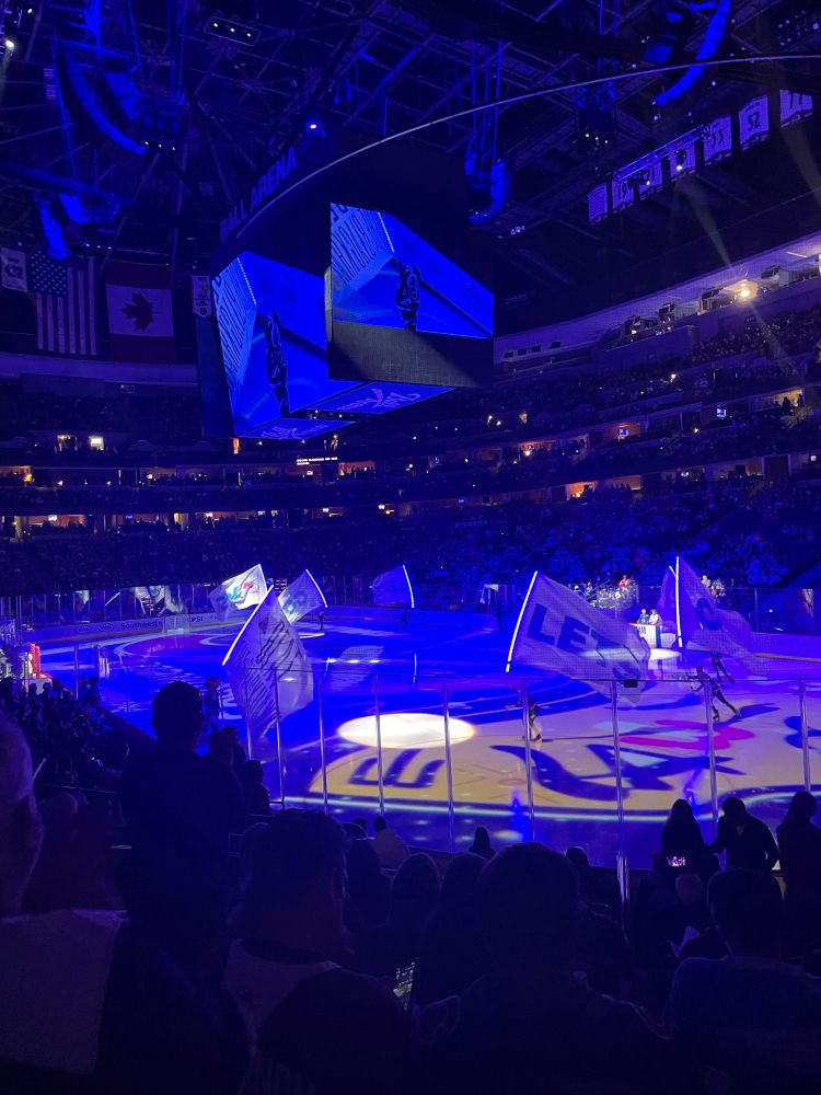 Ball arena right before start of game with blue lighting and the flags being skated along the ice