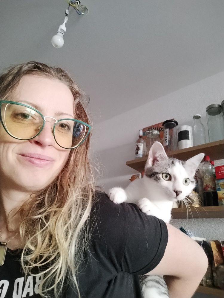 Cat sitting on the back of a woman, paying attention to something.