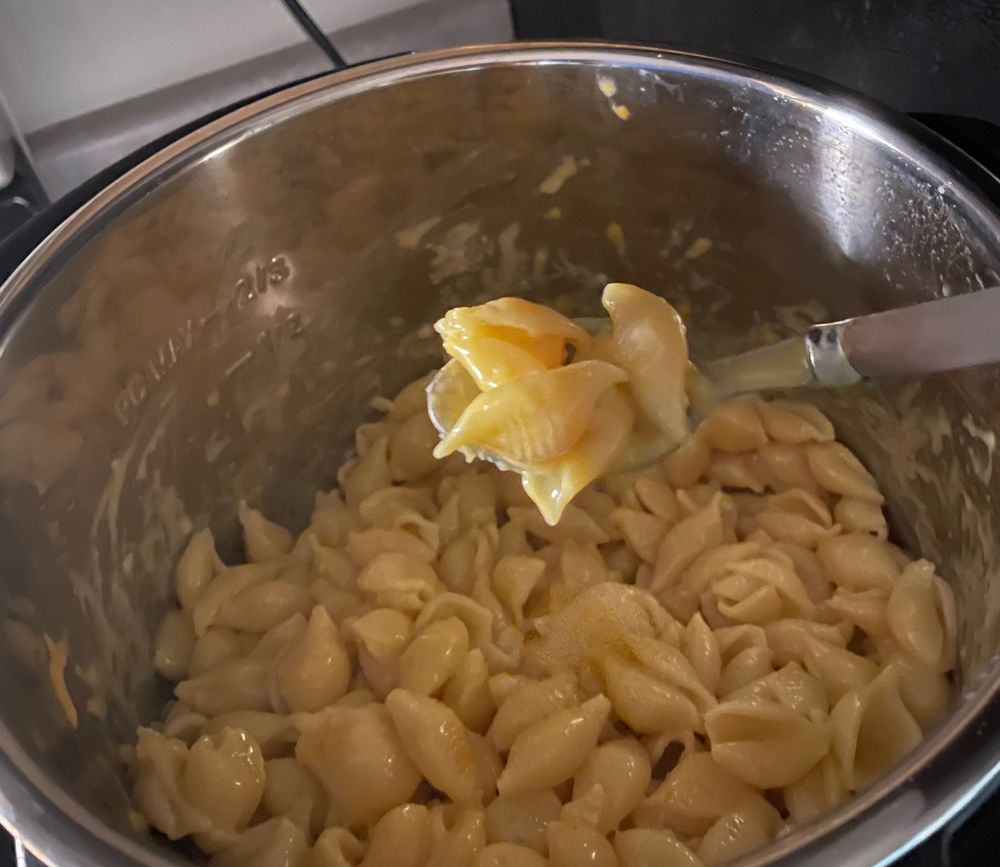 instant pot vegan mac and cheese and im holding a spoonful of it over the pot.