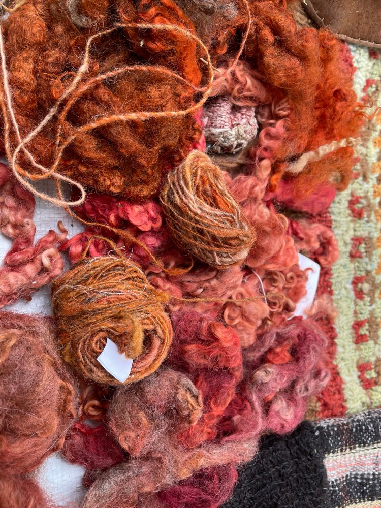 Samples of wool and yarn in various shades of peach, orange and pink
