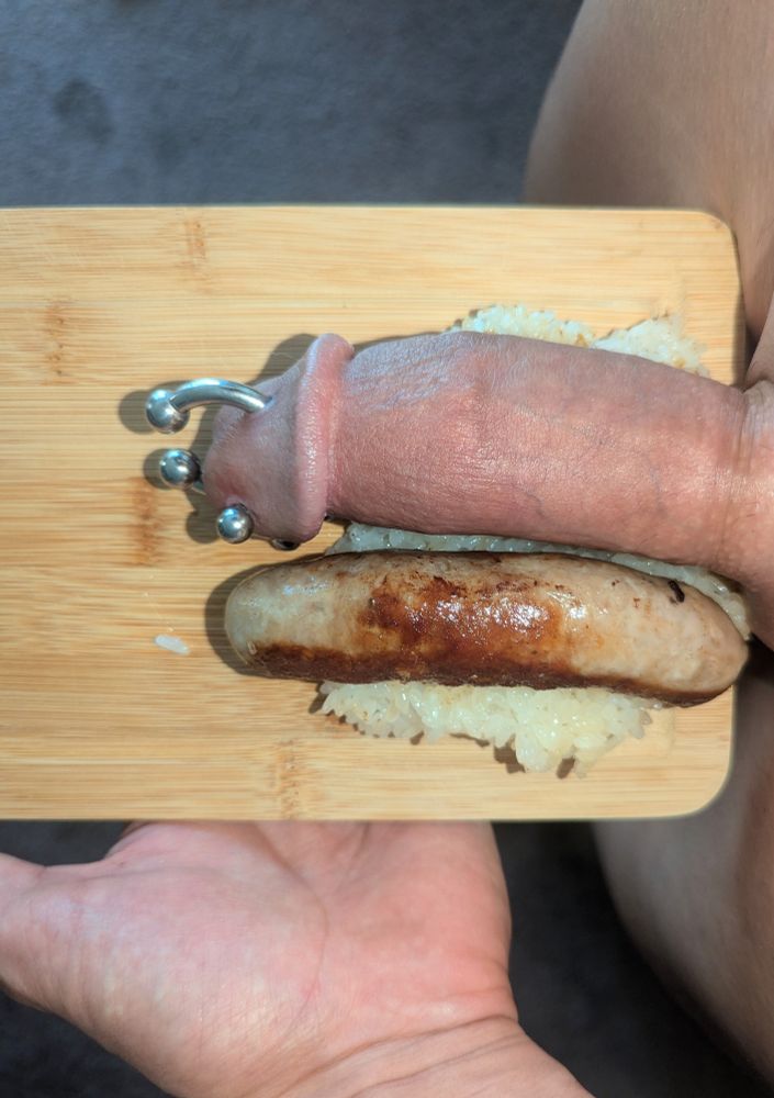 My thick pierced cock on a cutting board next to an Italian sausage on a bed of rice.  View from above POV