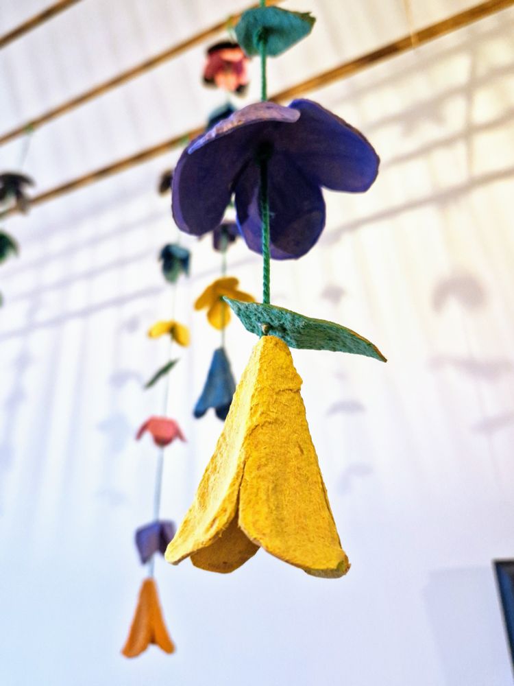 A close up photo of a yellow egg carton flower topped by a cardboard leaf.