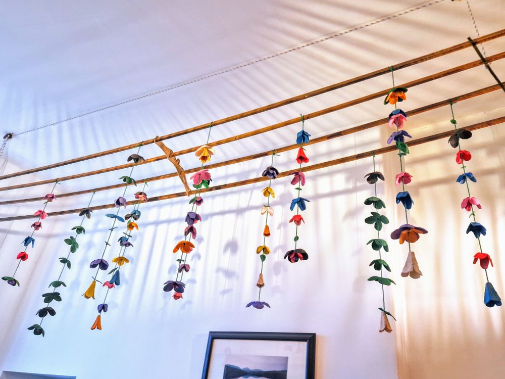 An old wooden drying rack hangs from the ceiling decorated with many strings of "flowers" made from egg cartons. They are painted all different colours and make beautiful shadows on the wall.
