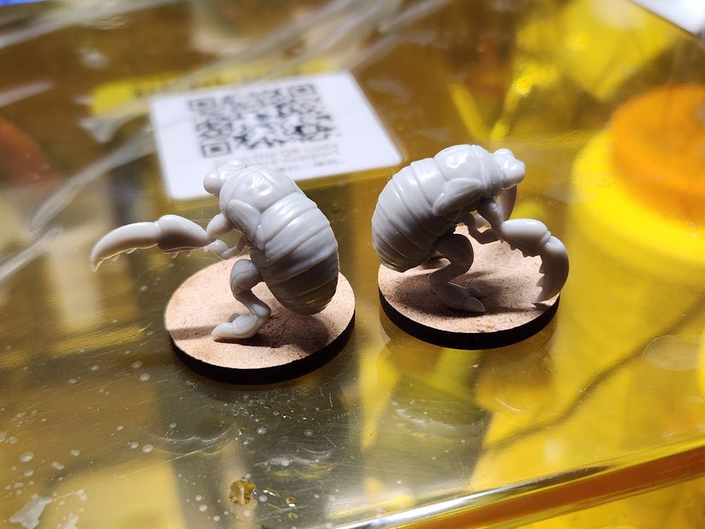 Two assembled cicada nymph beast models assembled, sitting atop a wash and cure 3.