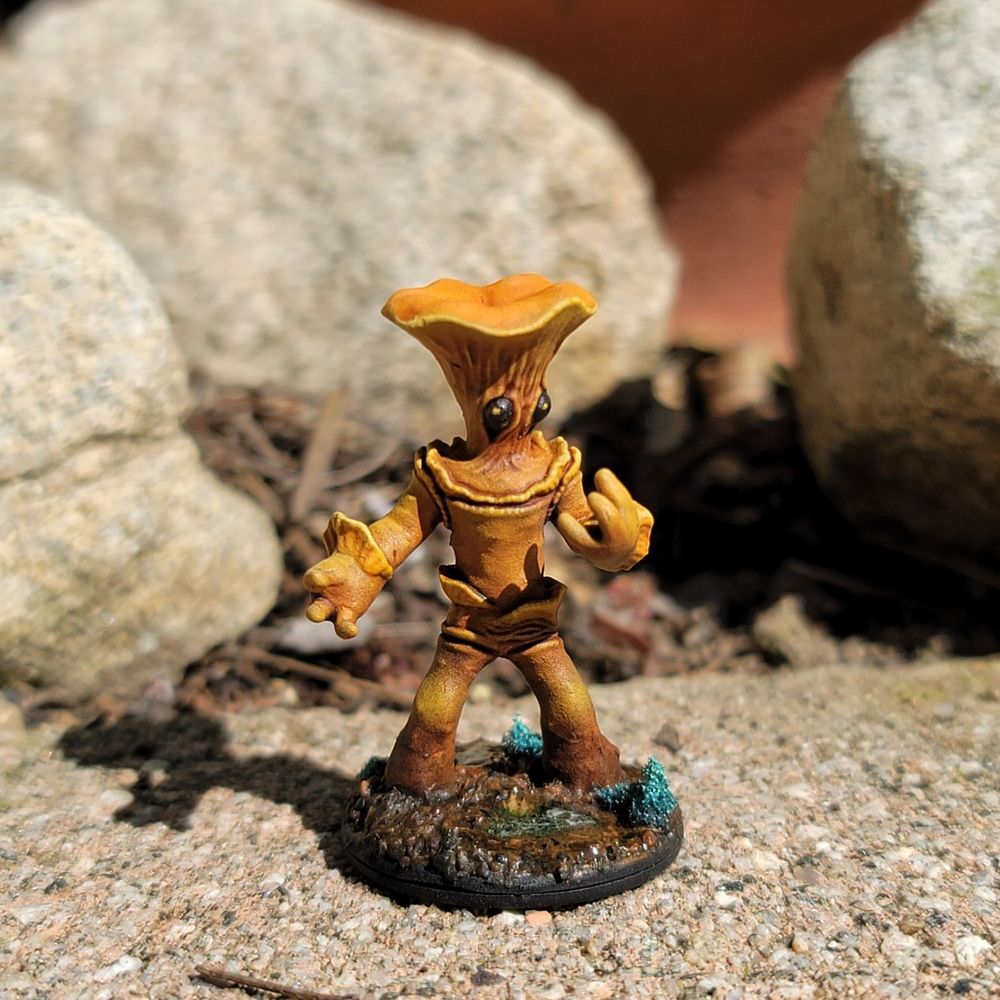 A painted 3d printed mushroom person miniature themed after a golden chanterelle mushroom
