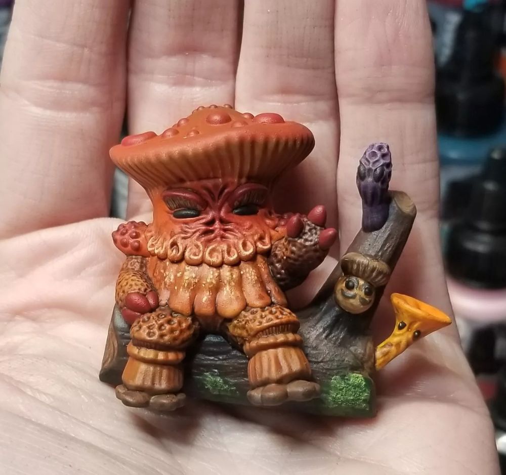 A painted 3D print of a very thick fungal king, a myconid monarch, sitting on a log with his three royal advisors, sitting in the palm of a human hand