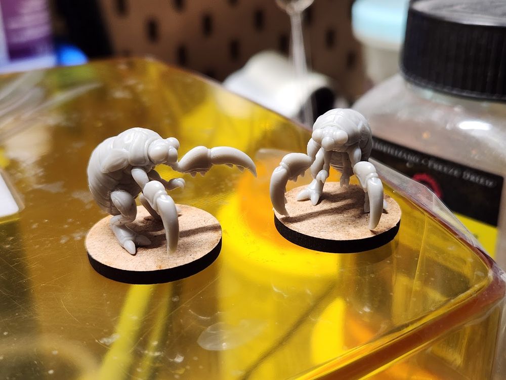 Two assembled cicada nymph beast models assembled, sitting atop a wash and cure 3.