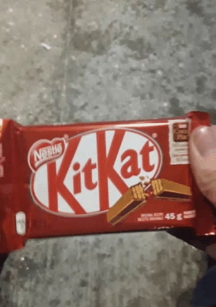 a person is holding a red kitkat bar in their hand