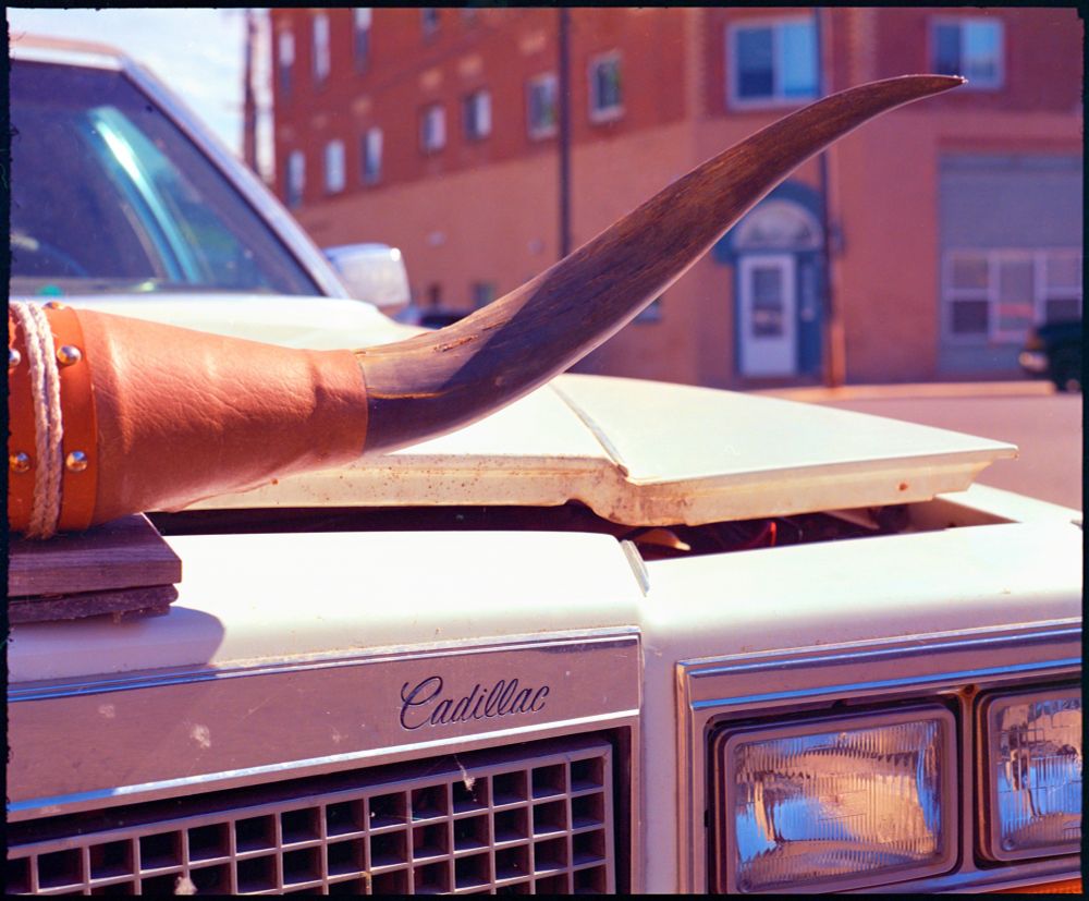 The front of an 80s Cadillac with bull horns above the grill. 