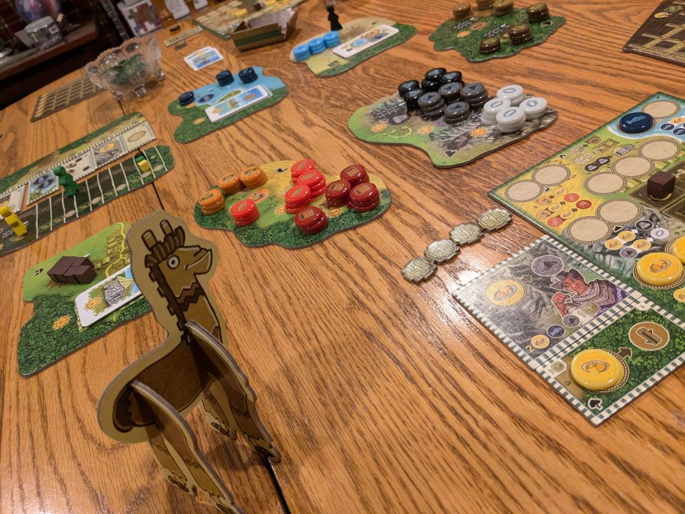 Table with the parts to the boardgame Altiplano, including a cardboard alpaca, variety shaped cardboard boards that represent parts of the forest