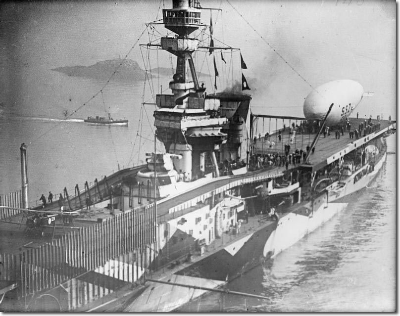 An airship sitting on the rear deck of the Royal Navy's favourite way to discover how not to build aircraft carriers, HMS Furious