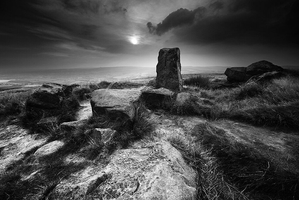 An upright stone bearing and incised cross, in an atmospheric moorland setting.