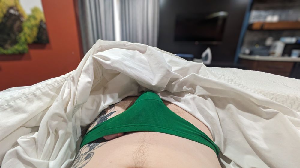Lying down, a photo with an erection poking out of green briefs.