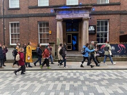 A group of people walking past a building on the street. 