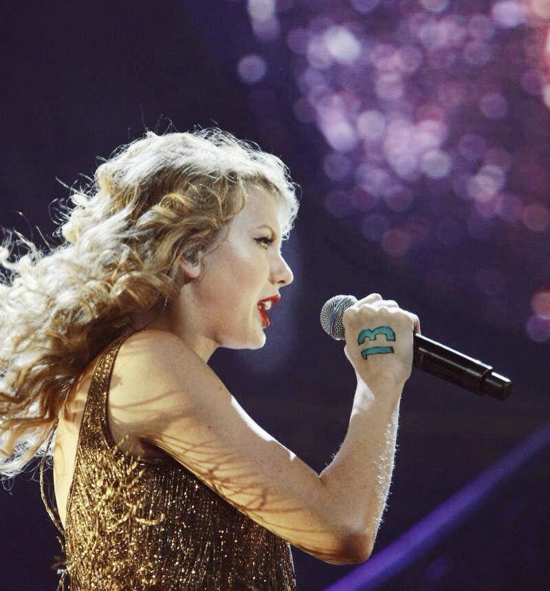 taylor swift in gold dress at speak now world tour, with 13 on hand