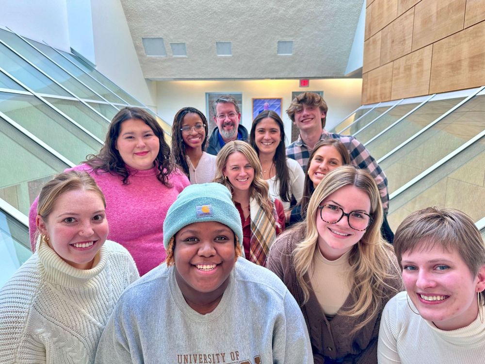 Twelve people line up in three rows inside the Reynolds Journalism Institute during news product thinking training led by Feli Carrique, pictured in the center.