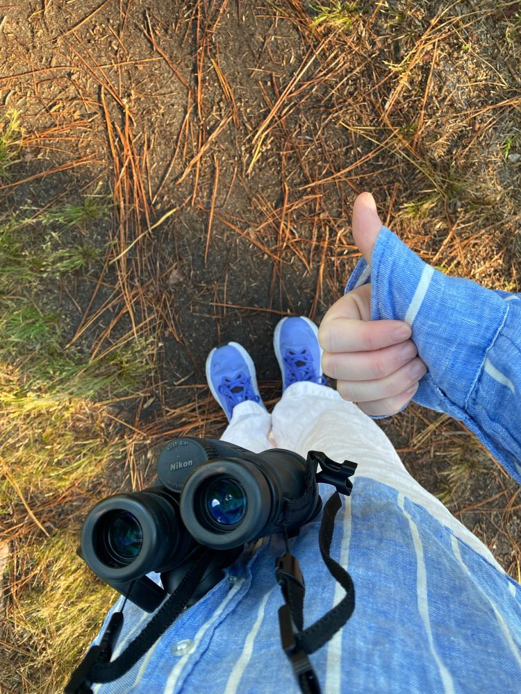 Looking down the author’s body, binoculars and clothing covering toes to hands