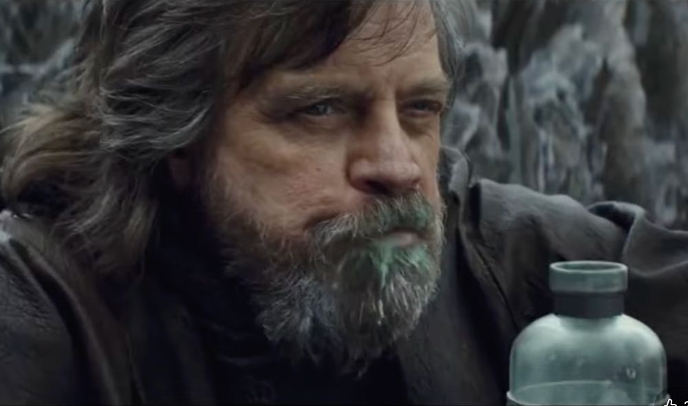 screenshot from the video- a clip of Luke Skywalker from the first Star Wars sequel movie, looking grim & flinty with a bunch of green milk dribbling out of his beard after he milks that giant walrus thing & drinks it