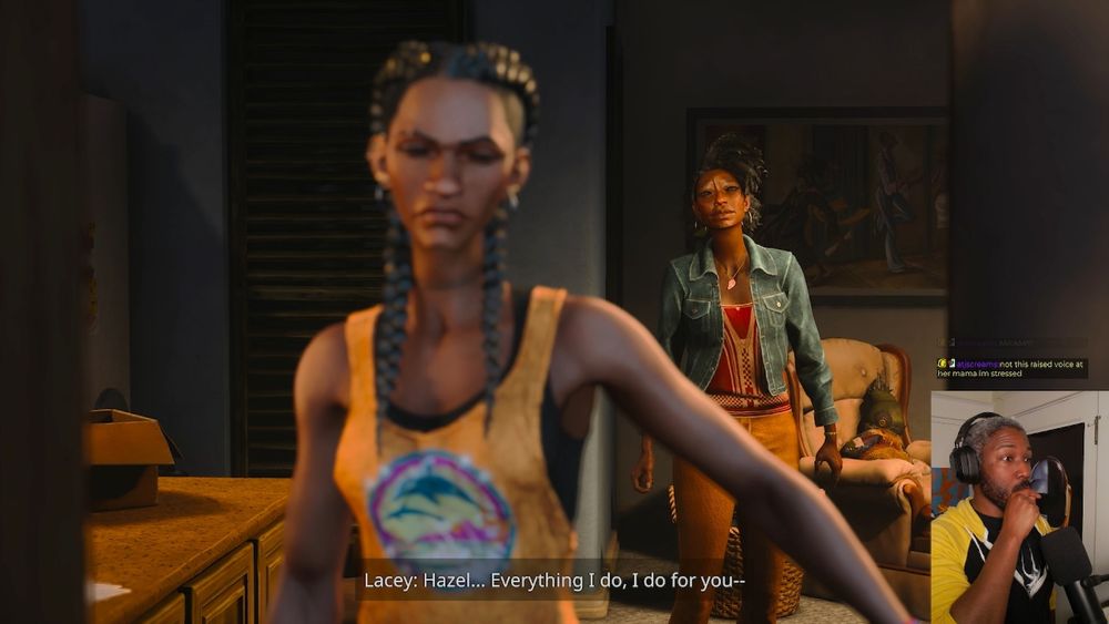 A snapshot from the Intelligame stream: Josh is in the lower-right hand corner, taken aback at the scene he's watching. In the game, Hazel and Lacey are in their trailer, preparing to evacuate for a storm. Hazel, a Black girl with thick braids and an orange tank-top, is walking away in disgust from her mother. Lacey, wearing a jean jacket with a red top and orange pants, is calling after her from the other side of living room. Lacey is captioned, saying: "Hazel...Everything I do, I do for you..."