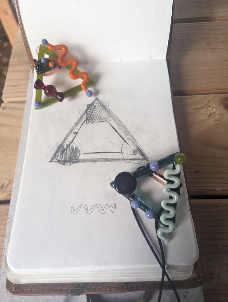 Glass pendants posed on a conceptual sketch of the same. 