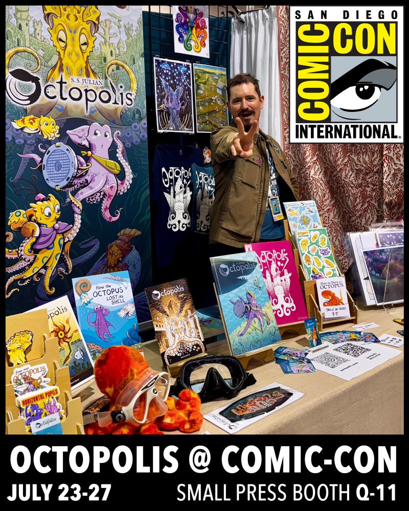 A photo of SS Julian behind a table of octopolis merch. Informational text about the event is displayed. Octopolis @ comic-con July 23-27 small press booth q-11