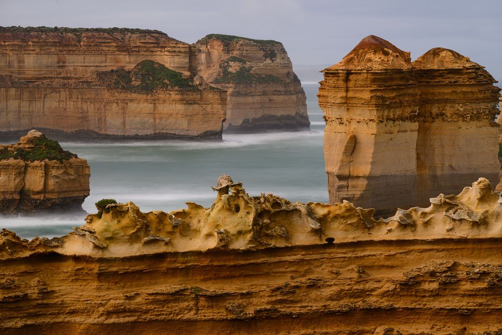 The Razorback in the foreground is a limestone stack that stands in a cove that is constantly subjected to the forces of wind and water erosion of the Southern Ocean. There is another limestone stack behind it to the left and right and further back are limestone cliffs