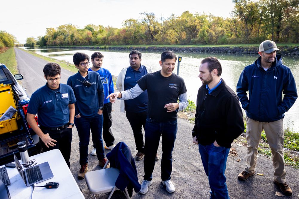 Karthik Dantu, center and pointing, speaks to students and Erie County engineers.