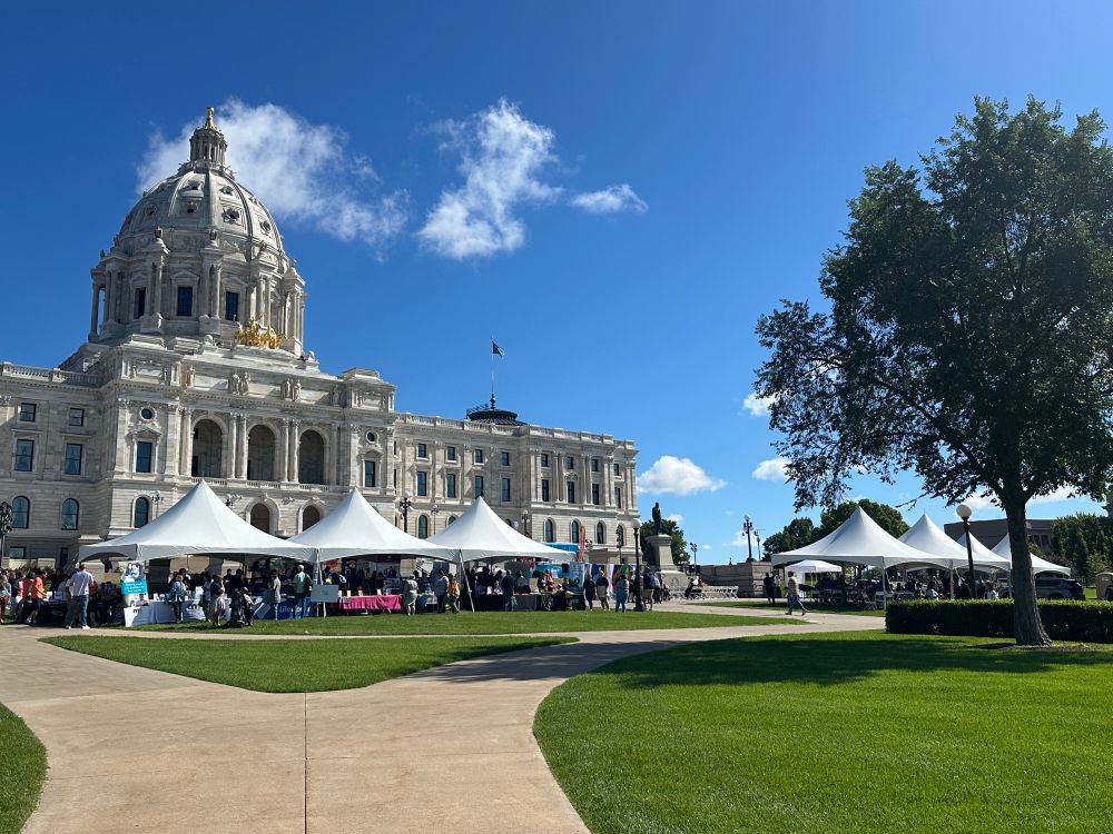 Several white tents and lots of people in front of the MN Capitol