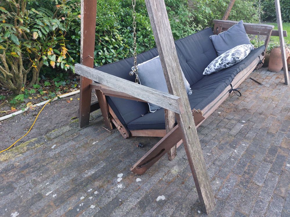 Schommelbank in een tuin waar de bodem uit is gestort van oudheid.