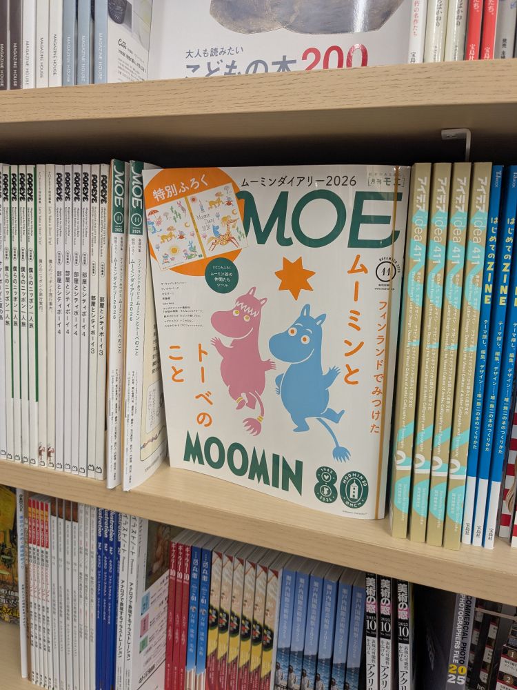 a moomin 80th anniversary edition of a monthly japanese magazine called MOE from october 2025. cover features a pink moomin with bangs and a blue moomin