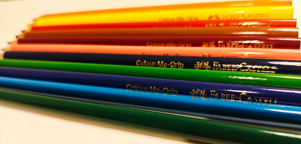 Colour pencils arranged on a sheet of paper - all colours from the rainbow and also brown.