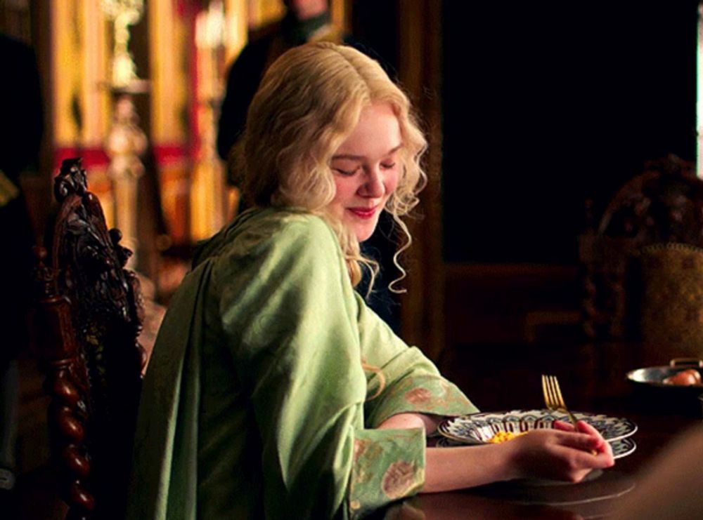 a woman in a green dress is sitting at a table with a plate of food