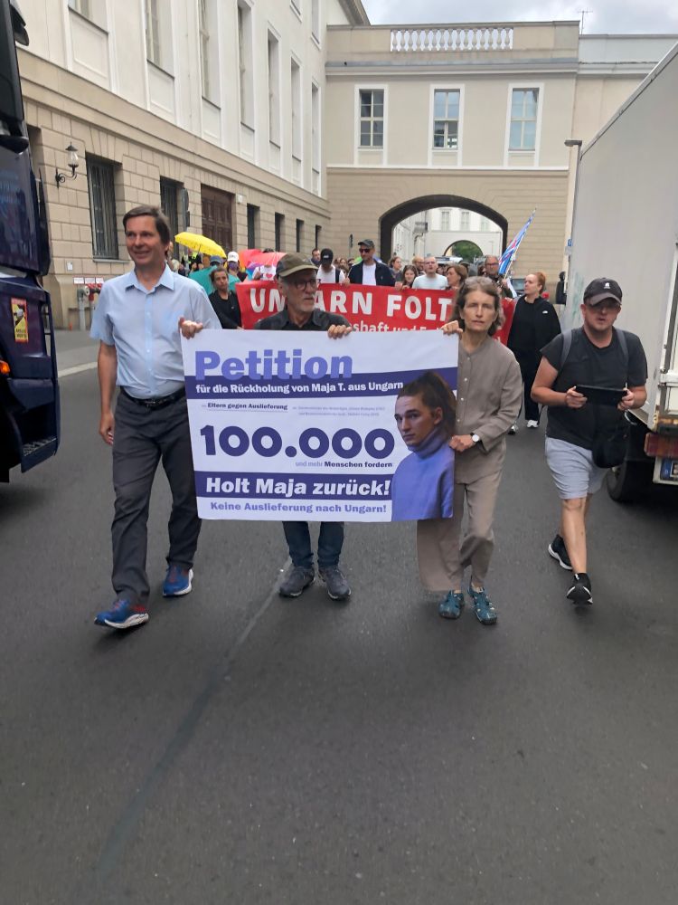 Foto des Protestmarschs. Jarosch trägt ein ein Banner mit der lesbaren Aufschrift: Petition, 100.000, Holt Maja zurück