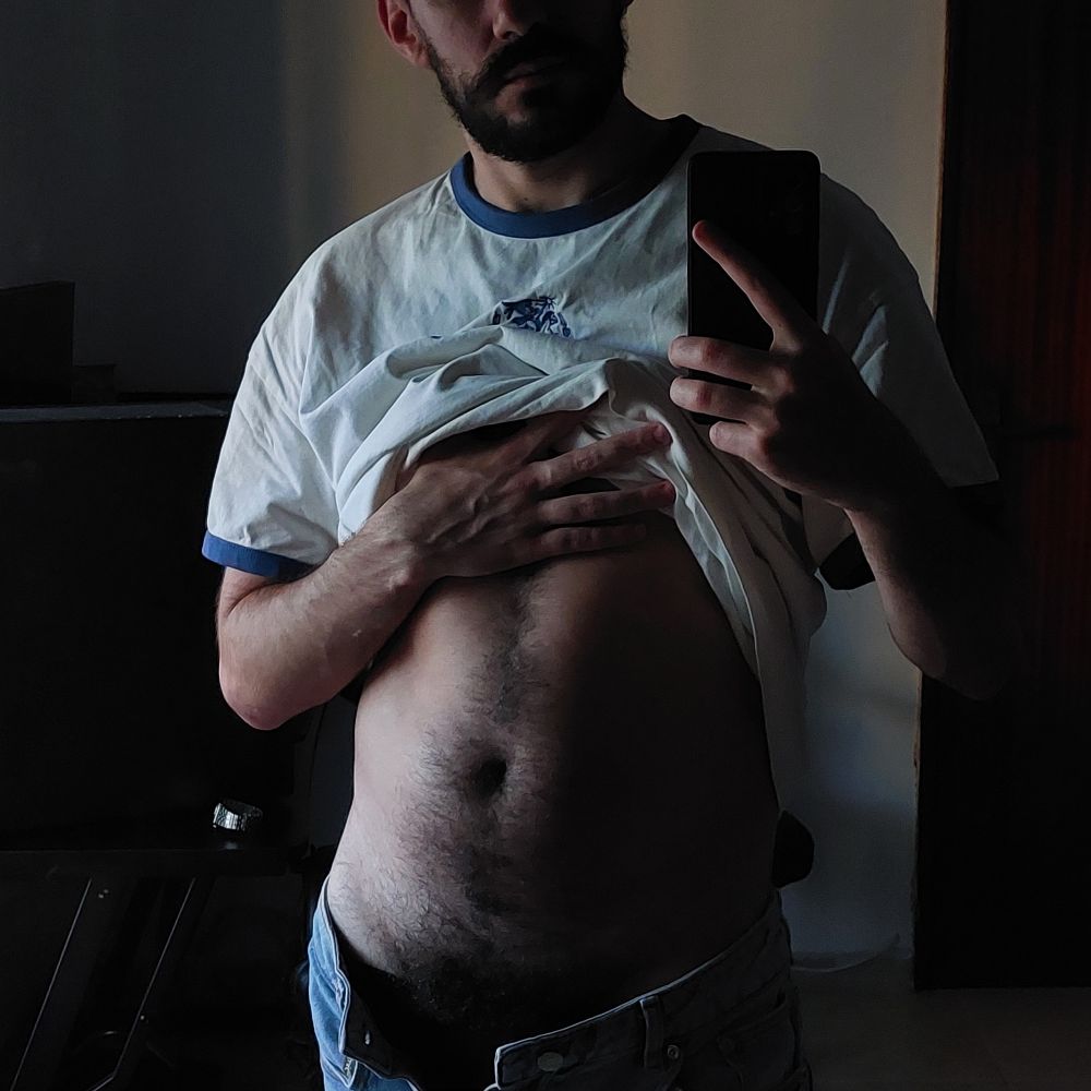 Mirror selfie with my tshirt pulled up, bush peaking from my open shorts, set in dim natural light